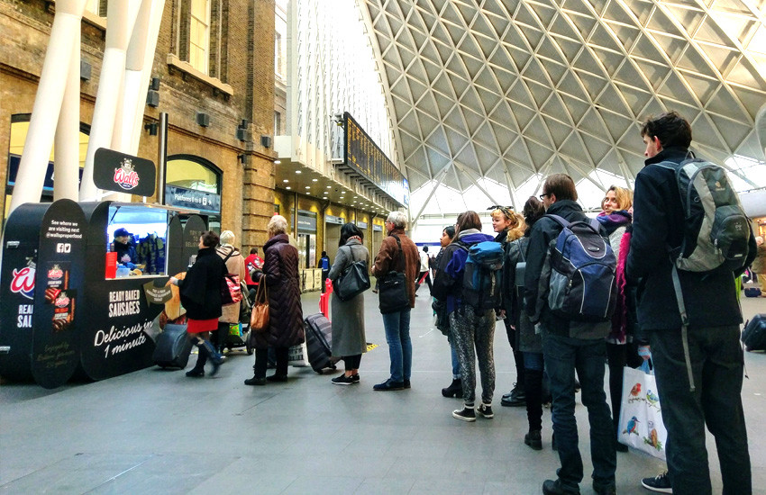 iMP provided a branded sampling pod & sampling staff to promote Wall's sausages iMP sampling agency distributing sausage sandwiches at Kings Cross Station for Wall's